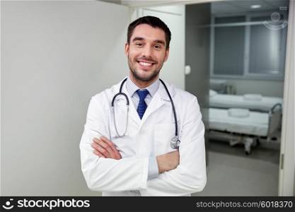clinic, profession, people, health care and medicine concept - smiling doctor with stethoscope at hospital corridor