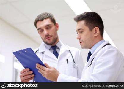 clinic, profession, people, health care and medicine concept - two doctors at hospital with clipboard