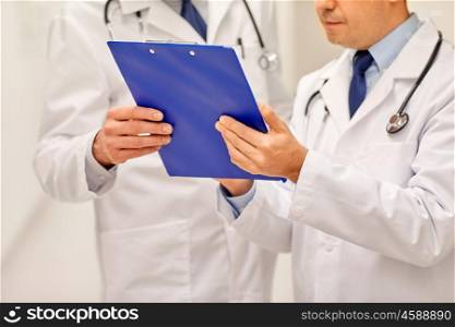 clinic, profession, people, healthcare and medicine concept - close up of doctors with clipboard at hospital