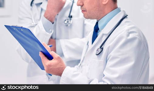 clinic, profession, people, healthcare and medicine concept - close up of doctors with clipboard at hospital. close up of doctors with clipboard at hospital