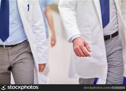 clinic, profession, people, healthcare and medicine concept - close up of medics or doctors walking along hospital