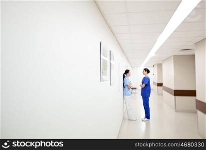 clinic, profession, people, healthcare and medicine concept - female doctors or nurses talking at hospital
