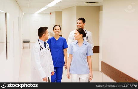 clinic, profession, people, healthcare and medicine concept - group of happy medics or doctors at hospital corridor