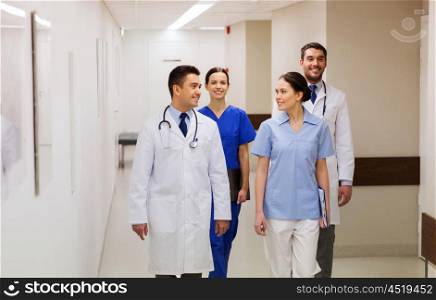 clinic, profession, people, healthcare and medicine concept - group of happy medics or doctors walking along hospital corridor