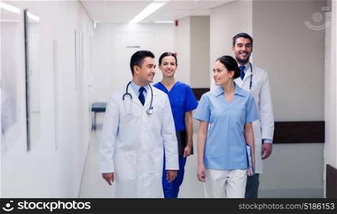 clinic, profession, people, healthcare and medicine concept - group of happy medics or doctors walking along hospital corridor. group of happy medics or doctors at hospital