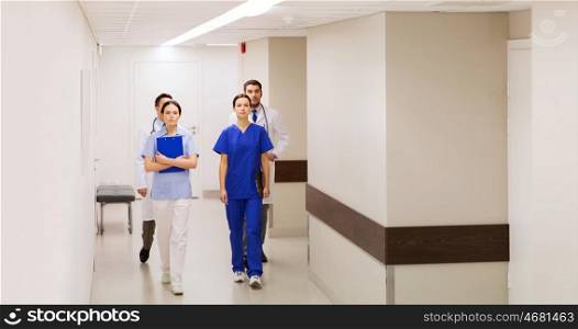 clinic, profession, people, healthcare and medicine concept - group of medics or doctors walking along hospital corridor