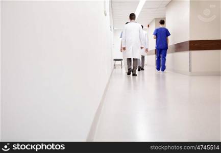 clinic, profession, people, healthcare and medicine concept - group of medics or doctors walking along hospital corridor