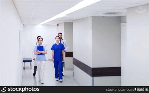 clinic, profession, people, healthcare and medicine concept - group of medics or doctors walking along hospital corridor. group of medics or doctors walking along hospital
