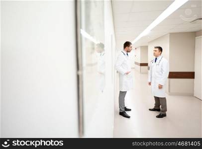 clinic, profession, people, healthcare and medicine concept - male doctors talking at hospital corridor