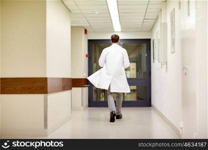 clinic, profession, people, healthcare and medicine concept - medic or doctor walking along hospital corridor