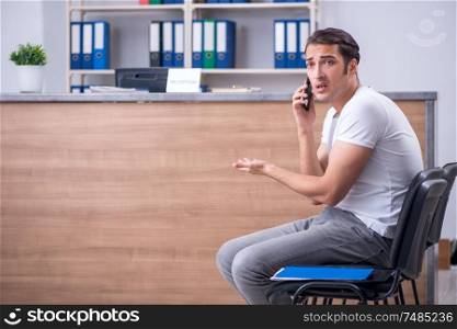 Clinic reception counter and young patient. Young man at hospital reception desk