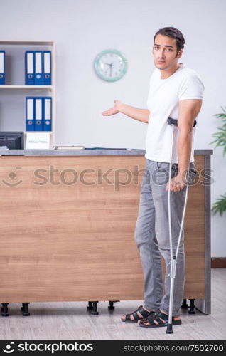 Clinic reception counter and young patient. Young man at hospital reception desk