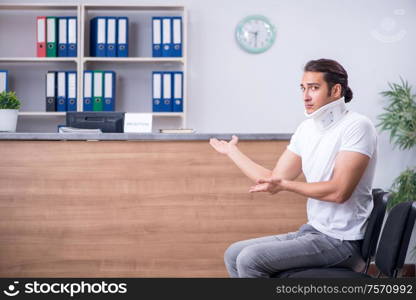 Clinic reception counter and young patient. Young man at hospital reception desk