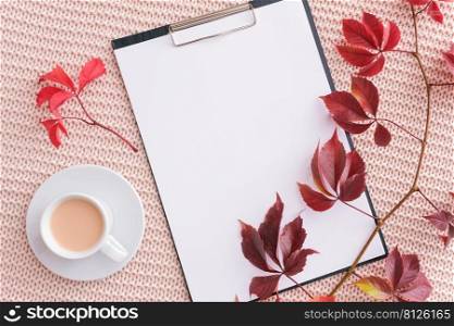 Clipboard, autumn leaves and cup of coffee with milk on pastel pink knitted plaid background. Autumn cozy. Flat lay, top view, mockup for your text.. Clipboard, autumn leaves and cup of coffee with milk on pastel pink knitted plaid background. Autumn cozy. Flat lay, top view, mockup for your text