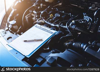 Clipboard on car with car insurance claim form for customer maintenance vehicle checklist in auto repair shop garage. Engine repair service concept. Business technical mechanics support for fixing car
