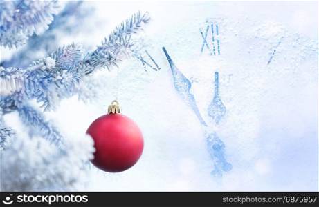 Clock and Red Christmas Ball Hanging on a Tree Branch in the Snow Winter Forest
