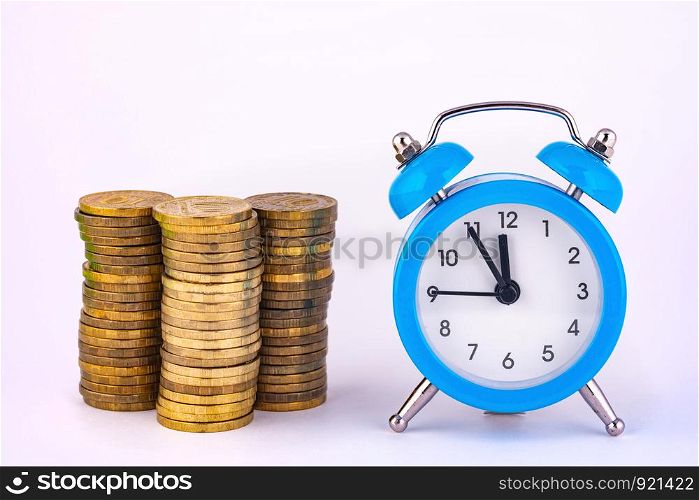 Clock and stacks of coins are close by, close-up
