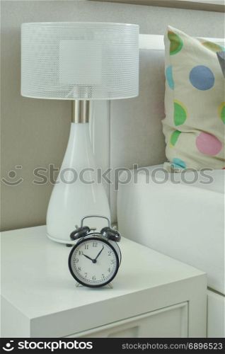 Clock and white lamp on bedside table in living room