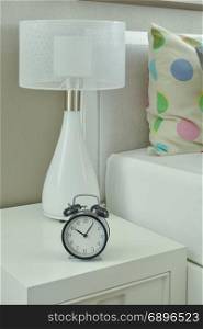 Clock and white lamp on bedside table in living room
