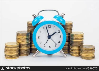 Clock in the foreground, stacks of coins in the background
