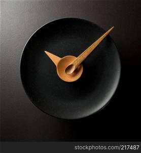 Clock made of wooden spoons on a black plate. eating time concept. eating time concept