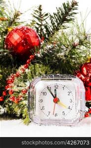 clock on snow under decorated christmas tree