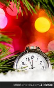 clock on snow with christmas tree branch on blurred background
