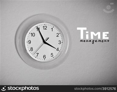 "Clock on the wall with "Time management" lettering, black and white photo"