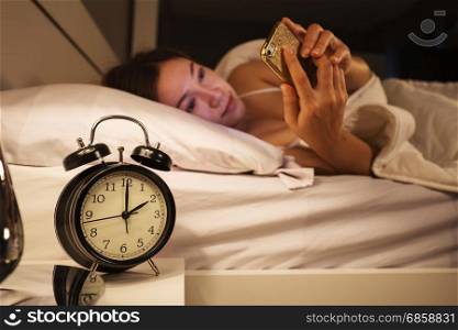 clock show 2 O&rsquo;clock and woman using her smartphone on bed in the bedroom