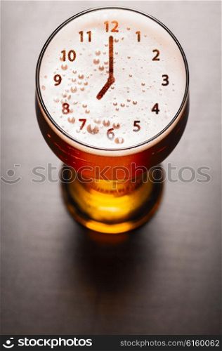 clock symbol on foam in beer glass on black table, view from above