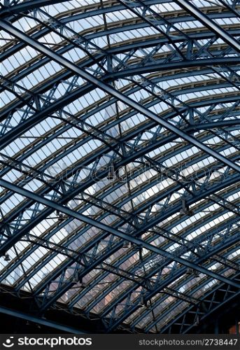 Clock tower of St Pancras station visible through the ornate glass roof of the entrance hall of the building