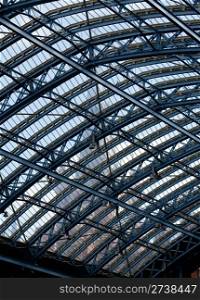 Clock tower of St Pancras station visible through the ornate glass roof of the entrance hall of the building