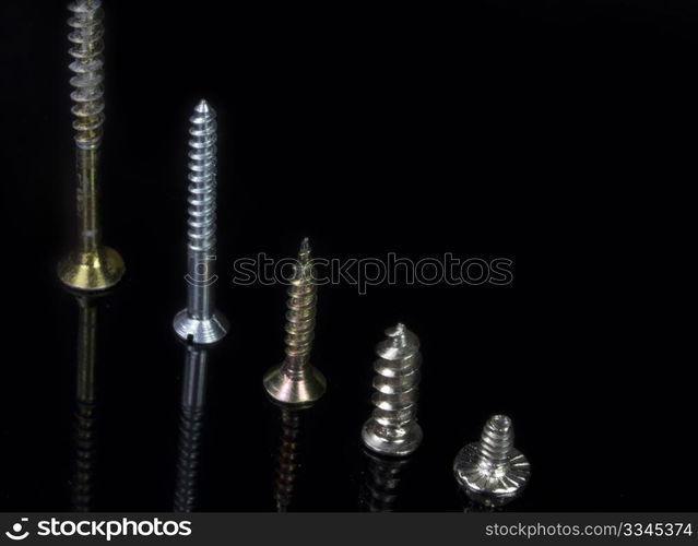 close five screws of various sizes in scale on black