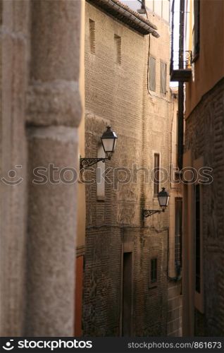 Close footpath between tall old houses with antique street lamps