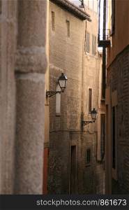 Close footpath between tall old houses with antique street lamps