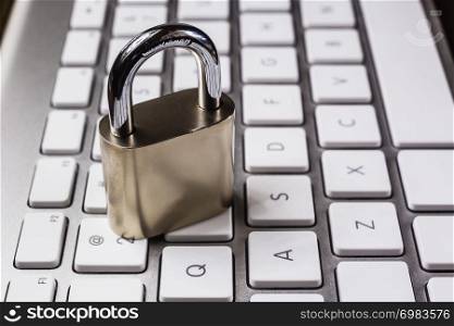 Close key padlock on white keyboard background, dim light dark tone. System access, encryption, online internet, password cracking, blockchain, cyber security, digital information protection.
