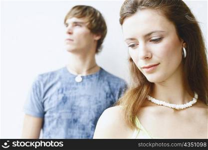 Close-of a young woman looking down with a young man behind her