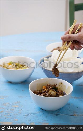 Close of human hand with chopsticks holding food