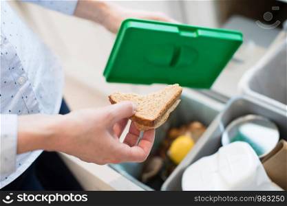 Close Of Woman Putting Food Waste Into Recycling Bin In Kitchen