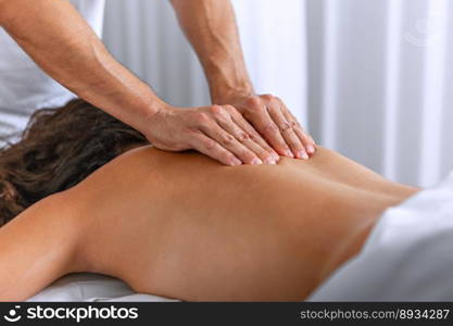 Close side view of relaxing woman lying face down on massage table receiving a back massage at spa center. Concept of spa.. Side view of relaxing woman lying face down on massage table receiving a back massage