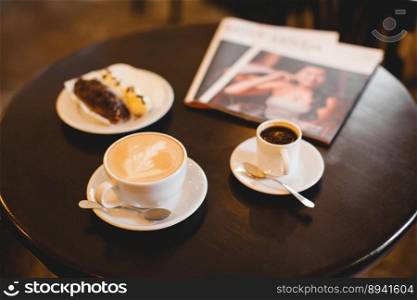 close up a mug of fragrant cappuccino and a sweet dessert and a magazine on the table