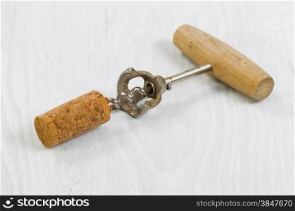 Close up an antique corkscrew with cork attached on white wood. Format in horizontal layout.