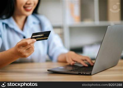 Close-up  and selective focus credit card in woman&rsquo;s hands, She holding a credit card while typing on laptop computer