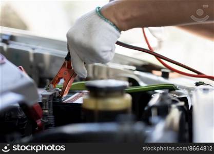 Close up and Selective focus of car mechanic holding battery electricity cables jumper for charging car battery, Services car engine machine concept