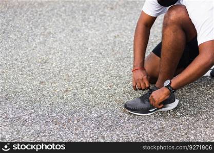 Close up Asian sport runner black man wear watch sitting he trying shoelace running shoes getting ready for jogging and run outdoor street health park with copy space, healthy exercise workout concept