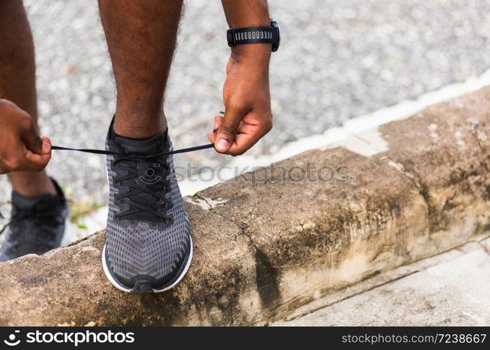 Close up Asian sport runner black man wear watch stand step on the footpath trying shoelace running shoes getting ready for jogging and run outdoor street health park, healthy exercise workout concept