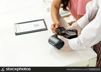 Close up Asian woman customer make contactless credit card payment after eating out in new normal social distance restaurant to reduce touching. Online contactless and technology concept.