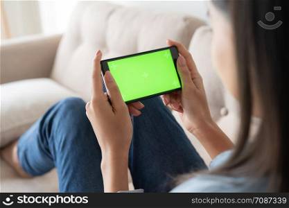 Close up asian woman hand touching smartphone screen green on sofa in living room at home