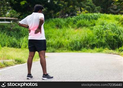 Close up Asian young sport runner black man wear watch feel pain on his spine low back and hip while running at the outdoor street health park, healthy exercise Injury from workout concept