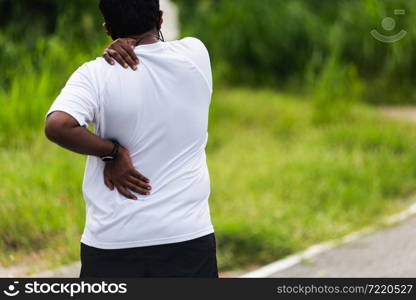 Close up Asian young sport runner black man wear watch hands joint hold back and shoulder he is pain while running at the outdoor street health park, healthy exercise Injury from workout concept
